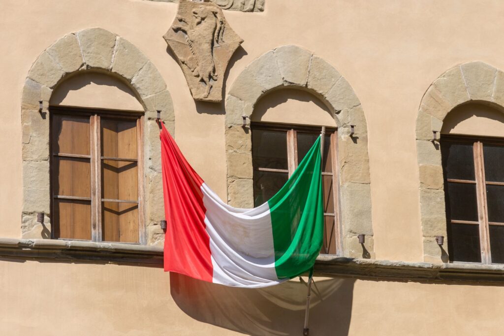 Bandera de Italia colgada en la fachada de un edificio histórico italiano