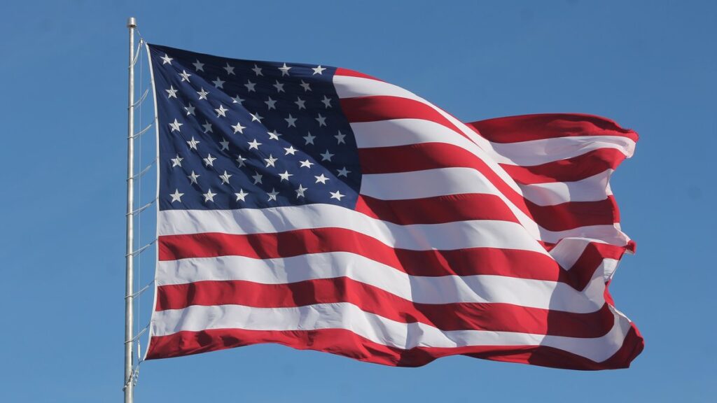 Bandera de Estados Unidos flameando contra un cielo celeste despejado