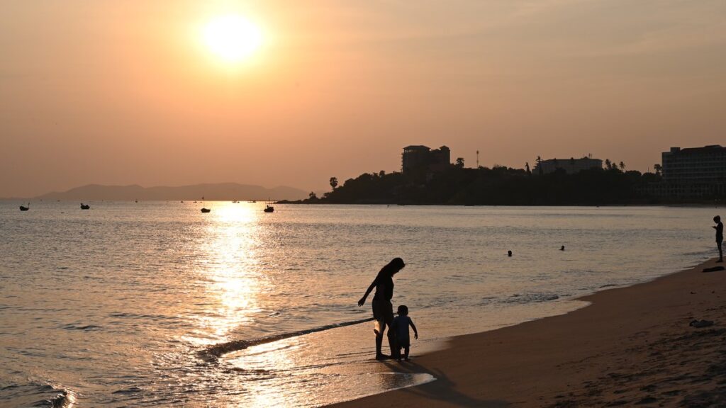 Adulto y niño en silueta caminando por la orilla del mar al atardecer