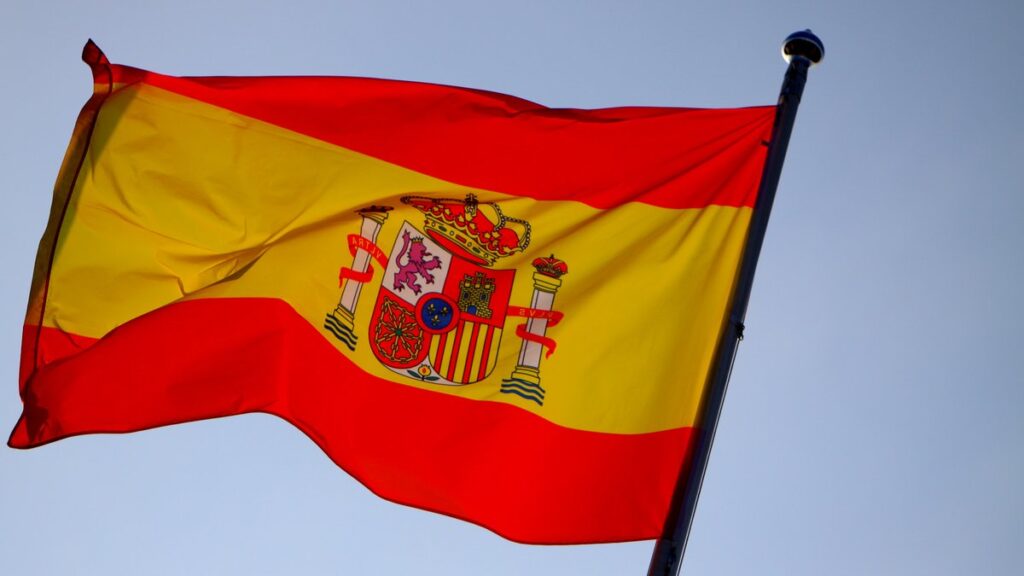 Bandera de España flameando en primer plano contra un cielo despejado